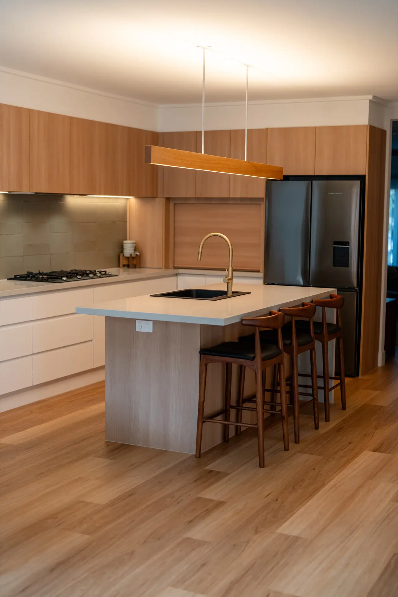 A warm oak kitchen with a stone island and timber bar stools