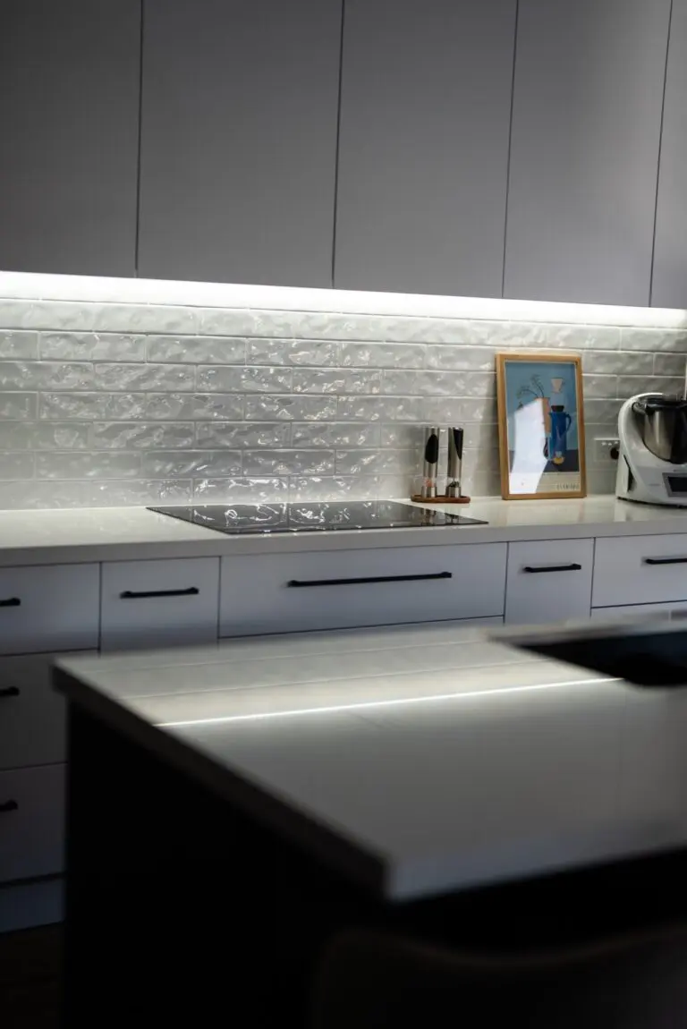 A white kitchen bench with a light splashback and personal photographs